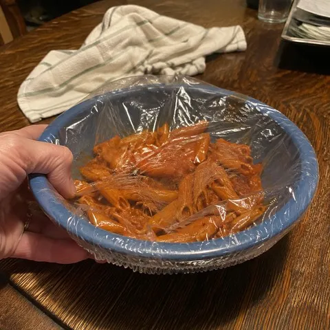 Covered pasta bowl on a dining table