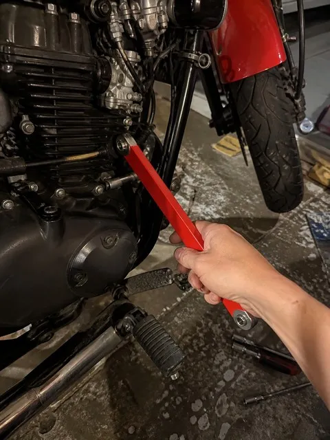 Red offset extension wrench used beside a motorcycle engine