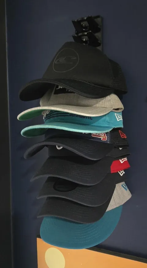 Black wall organizer holding a compact stack of caps