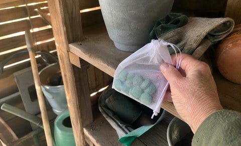 Mesh pouch being placed in a garden storage shed