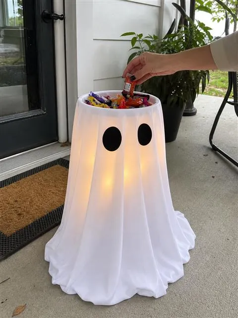 White glowing ghost candy bowl on a daytime porch while candy is added