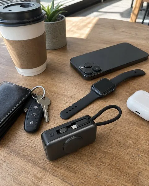 Black 3-in-1 charger carried with phone watch and earbuds at a coffee shop