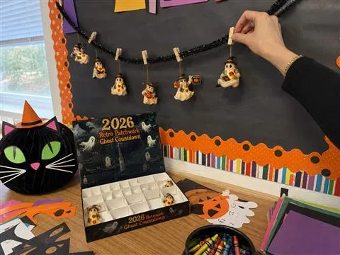 Teacher arranging flat ghost ornaments on a classroom garland