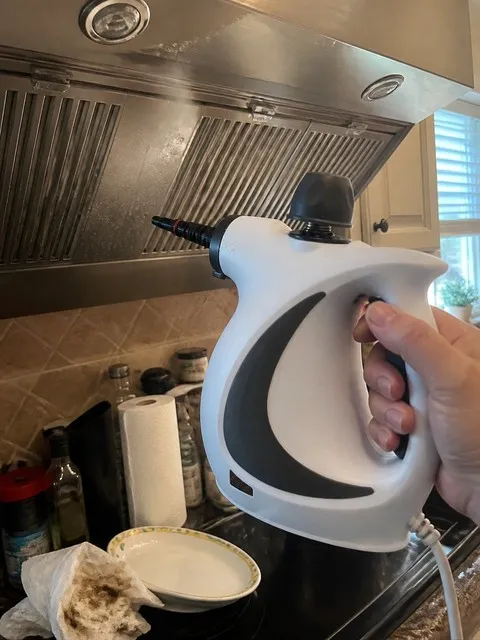 Handheld steam cleaner used under a kitchen range hood