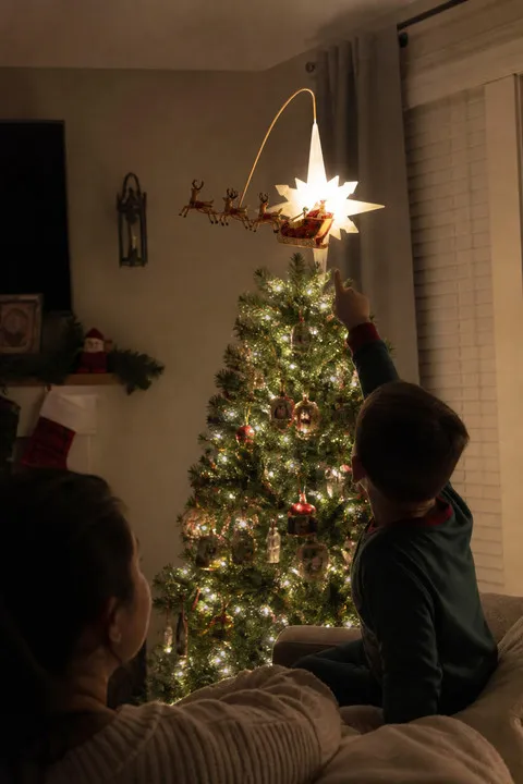 Child pointing at the glowing animated tree topper at night