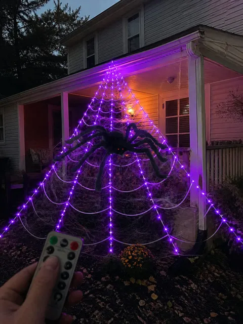 Glowing spider web decoration on a suburban porch at dusk
