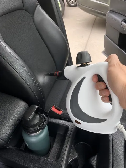 Handheld steam cleaner used on a vehicle seat seam