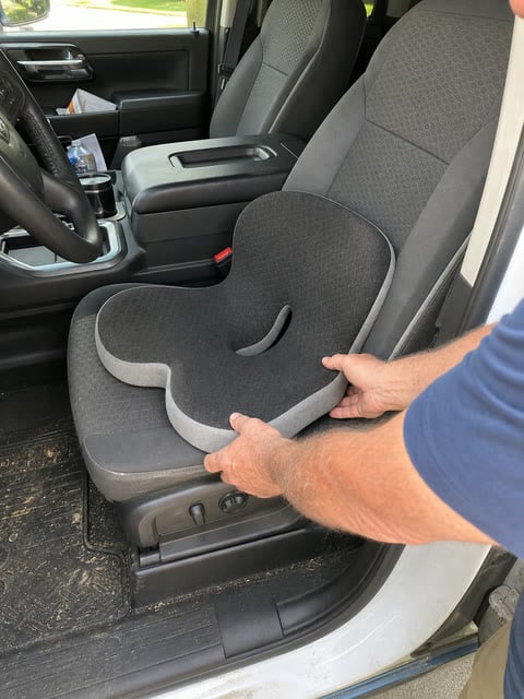 Integrated support cushion being placed on a pickup truck seat