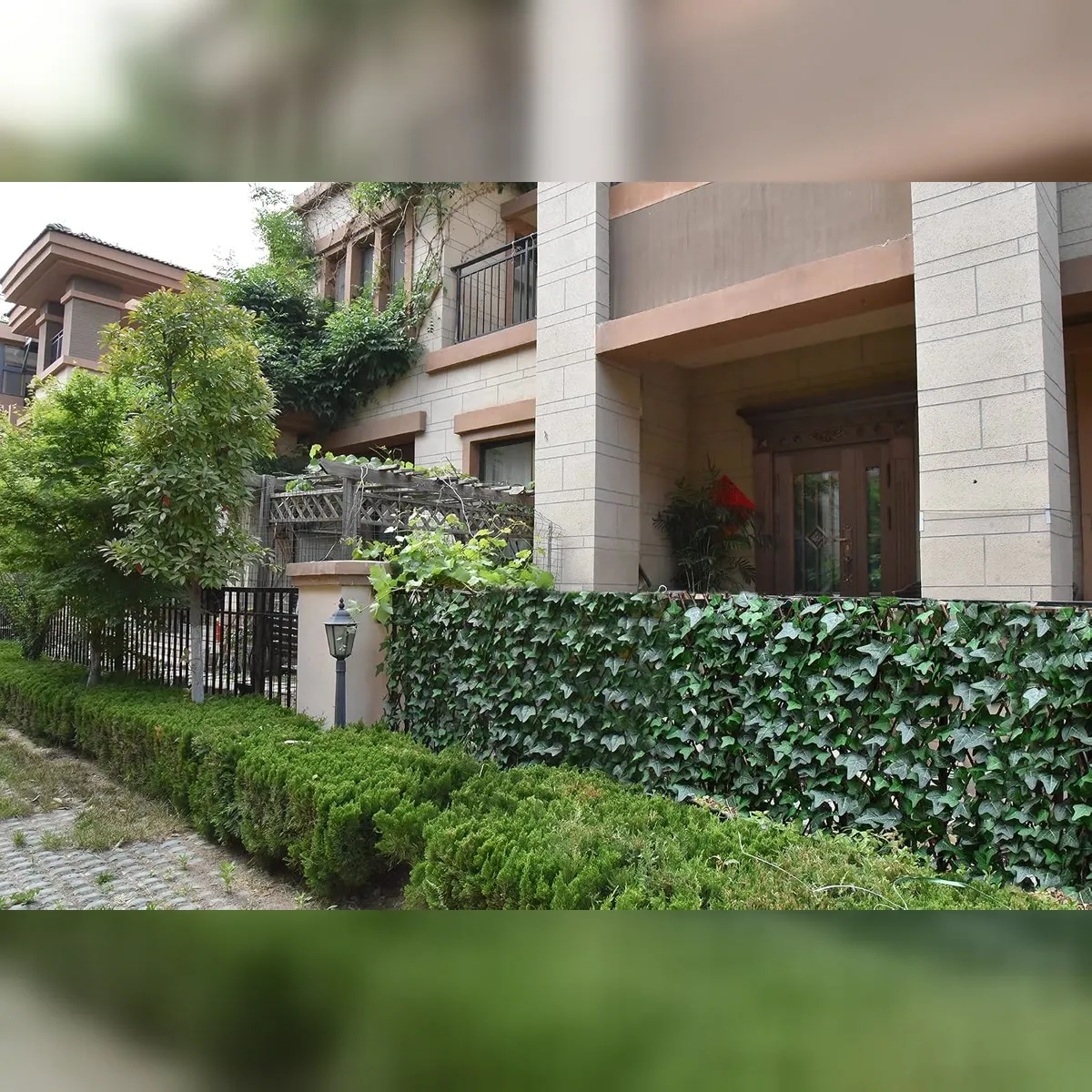 Expandable faux ivy panels adding greenery to a front garden fence