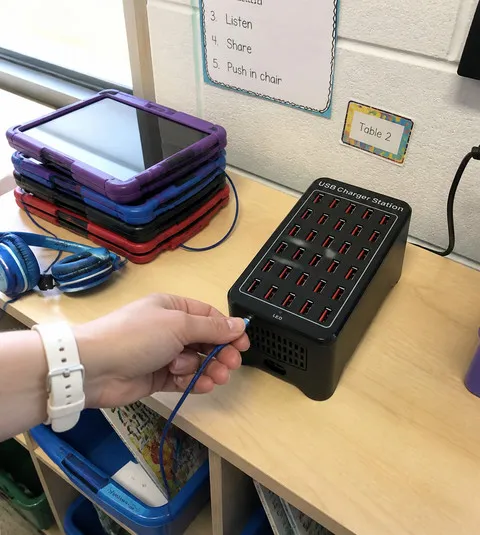 Teacher connecting a classroom tablet charging cable