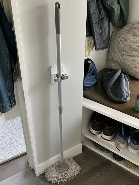 Mop stored vertically beside a family mudroom bench