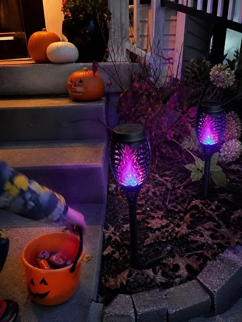 Two multicolor solar torches beside a Halloween porch