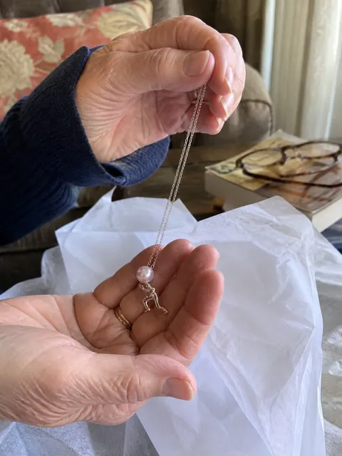 Silver-tone pearl pusher necklace opened as a milestone gift