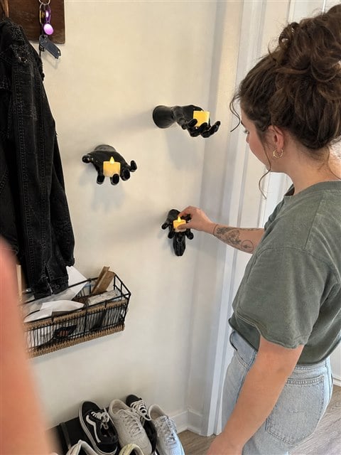 Three black hand candle holders in a lived-in apartment entryway