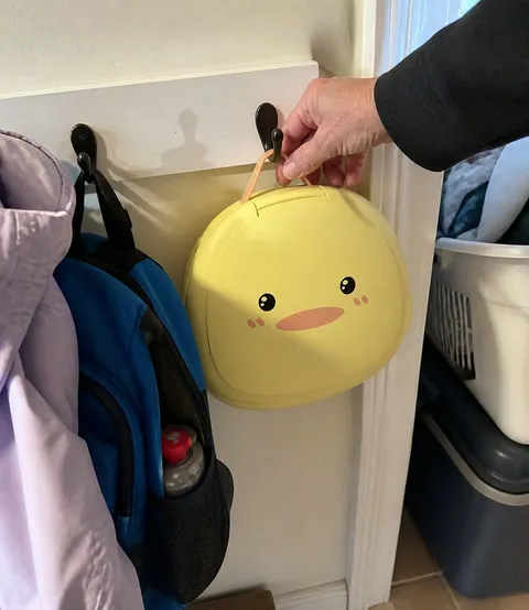 Folded duck travel potty hanging neatly in a family utility closet
