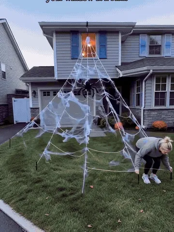 Purple and orange spider web lights glowing in a Halloween yard display