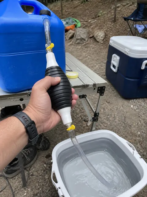 Manual siphon pump moving water at a campsite