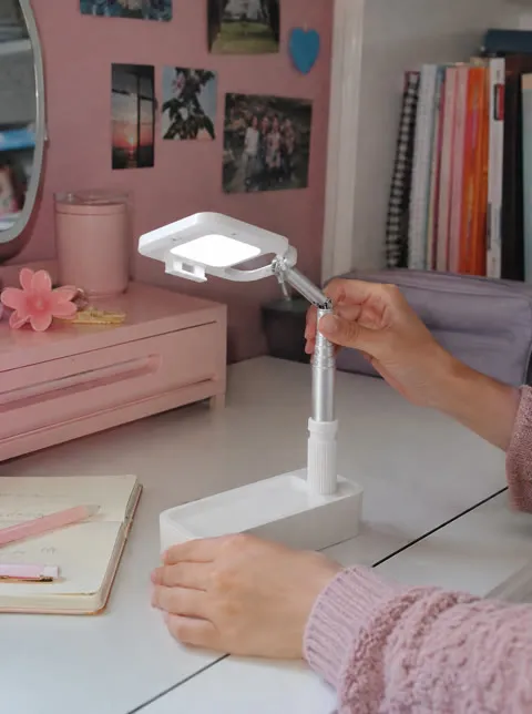 Folding phone stand being adjusted in a bedroom study area