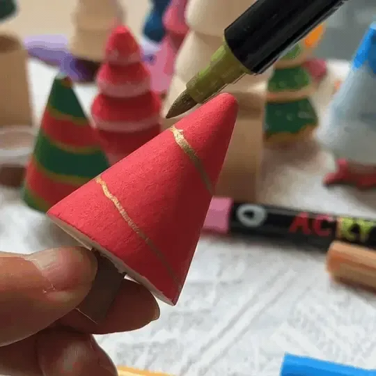 A person is painting mini Christmas trees pink for Pinkmas.