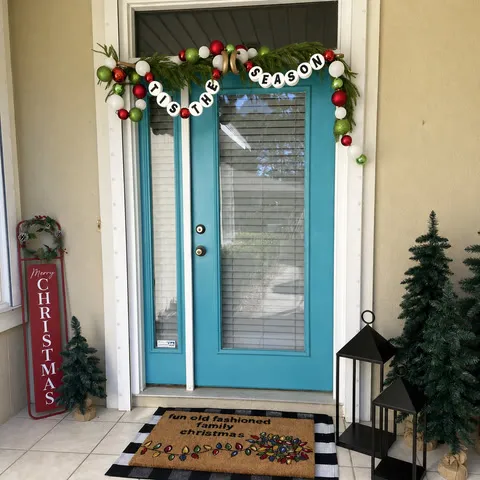 Gold adjustable hanger holding Christmas garland above turquoise double doors
