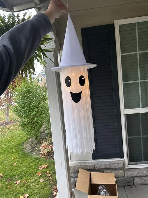White light-up tassel ghost being hung on a front porch