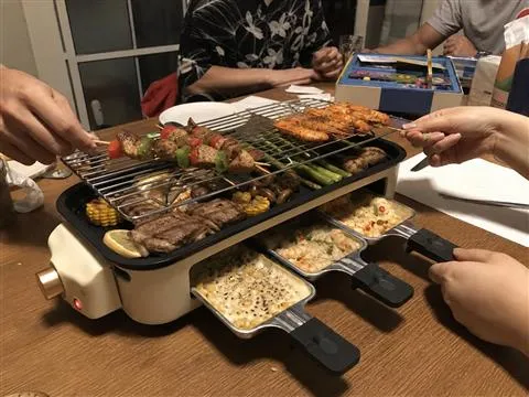 Friends sharing skewers around the electric grill at game night