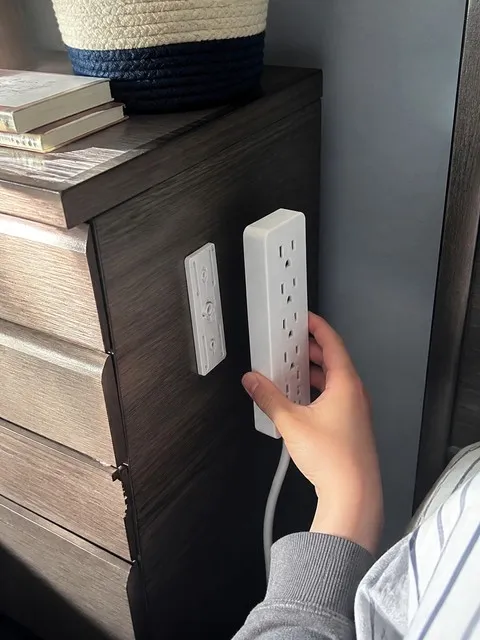 Power strip mount beside a bedroom dresser