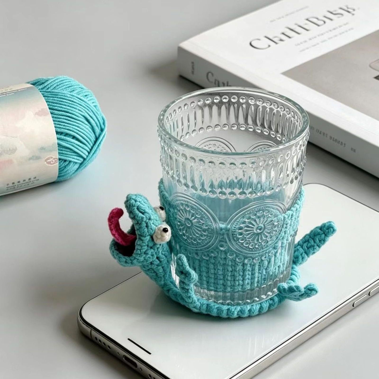 Glass mug resting comfortably inside an absorbent teal reptile drink mat over a phone