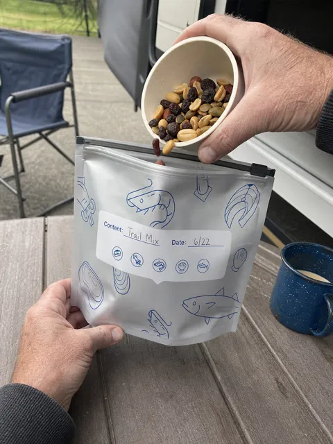Older camper pouring trail mix into a reusable foil pouch