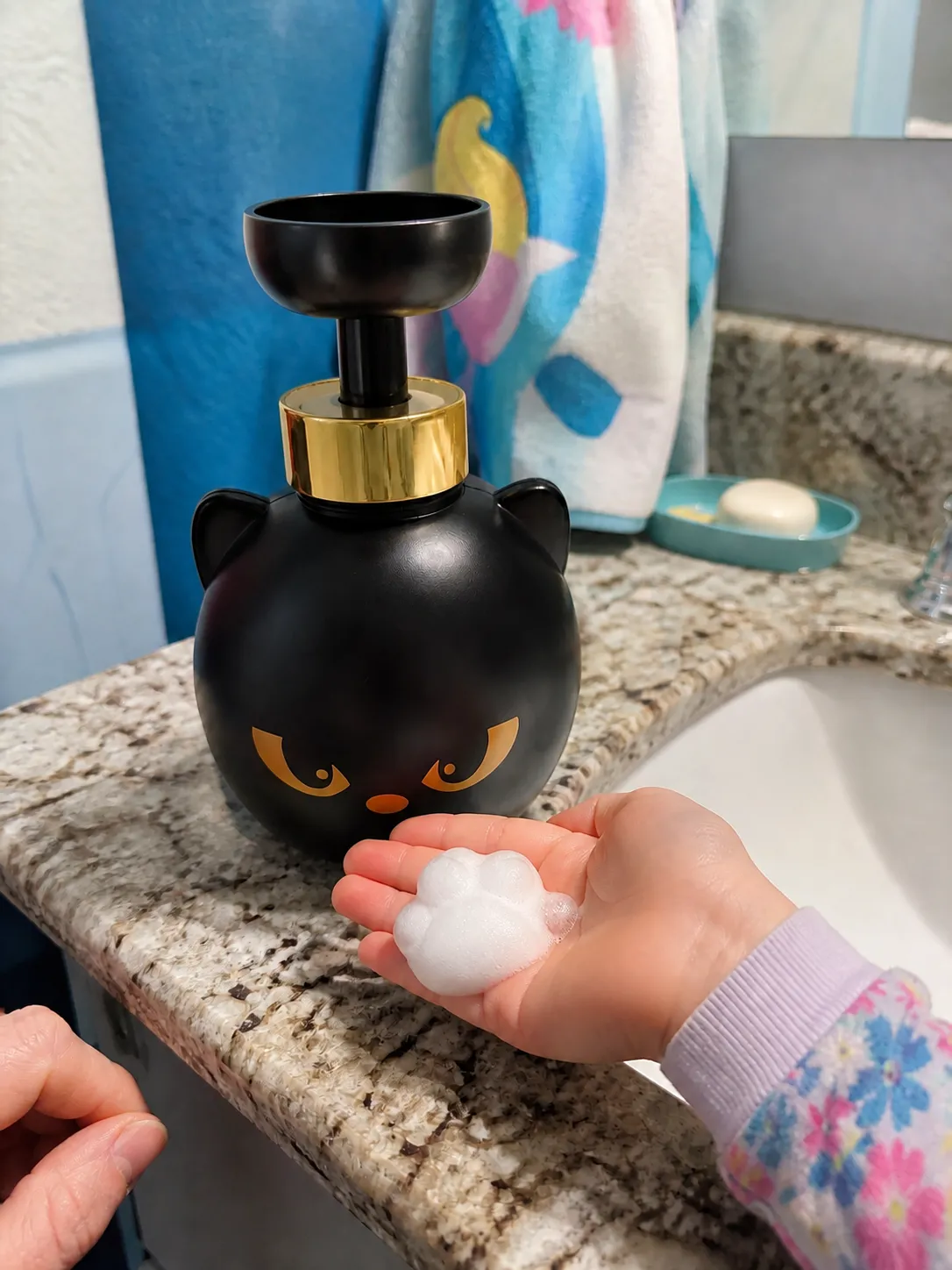 Child holding paw-shaped foam in a colorful bathroom
