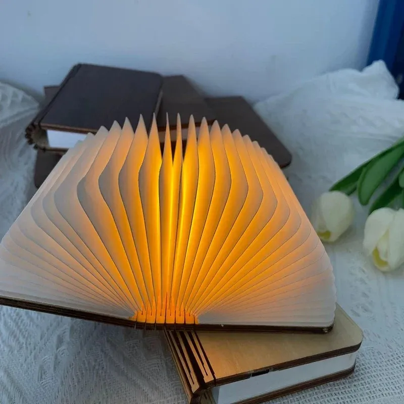 Open book light glowing beside books in a bedroom