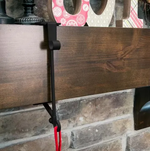 Black adjustable hanger installed on a wood mantel
