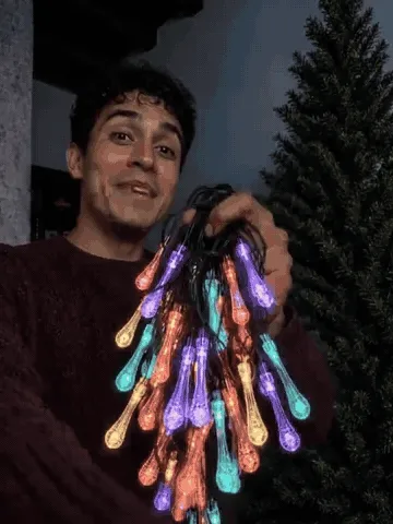 Multicolor waterdrop string lights decorating a tree, porch, and staircase