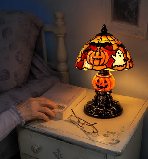 Halloween lamp glowing beside reading glasses and a book
