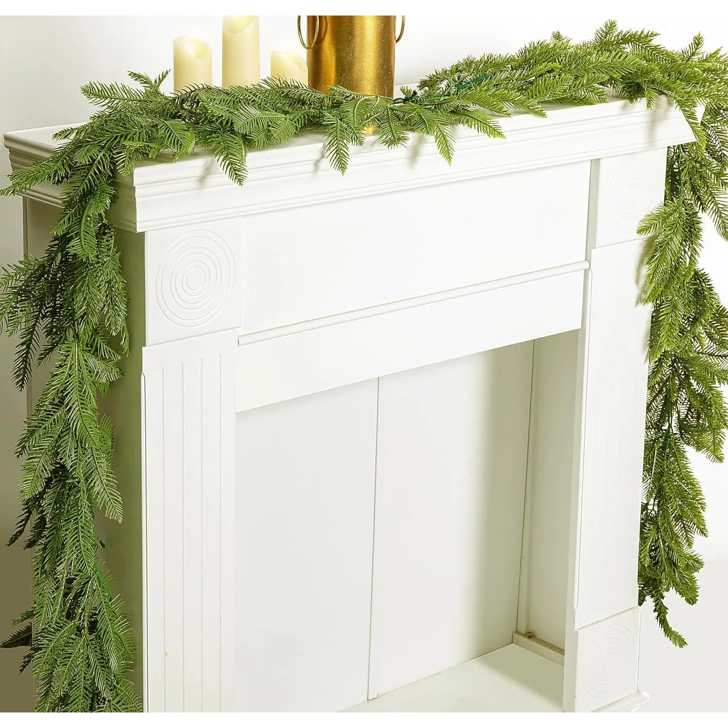 Artificial Norfolk pine garland cascading over a white mantel