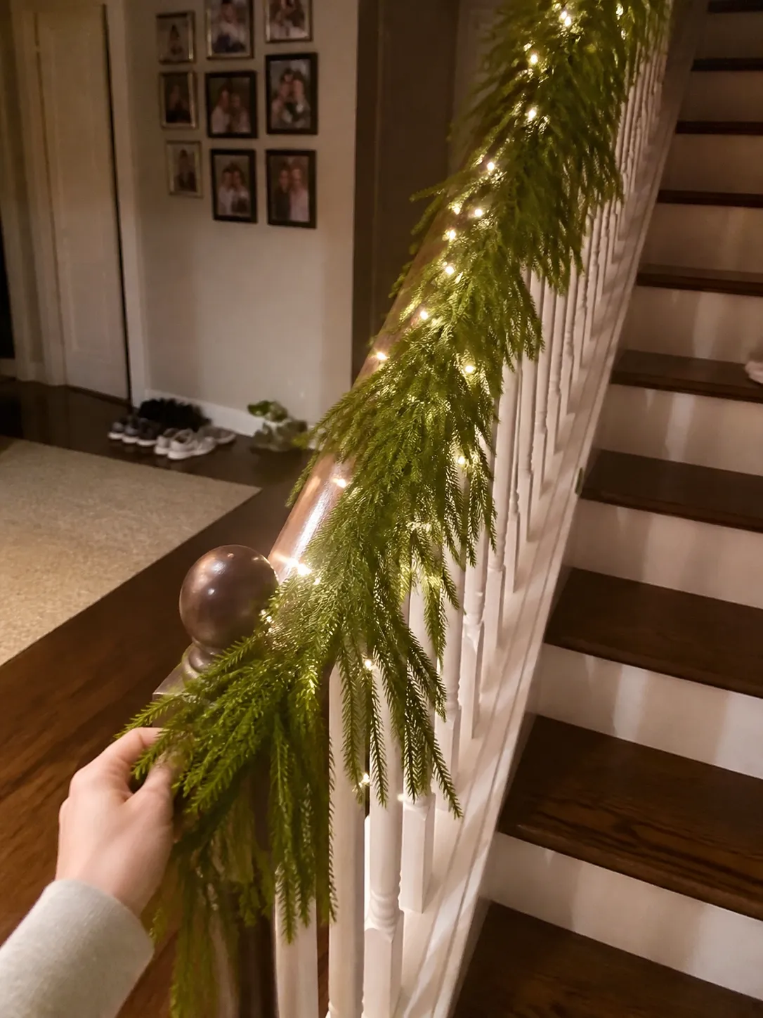 Warmly lit garland being arranged along a stair railing