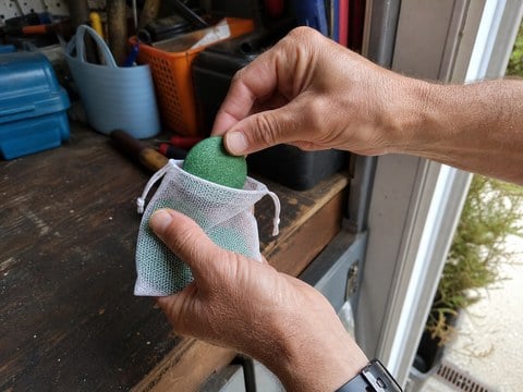 Homeowner filling a mesh pouch on a garage workbench