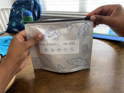 Parent using the slider on a labeled snack pouch at a dining table