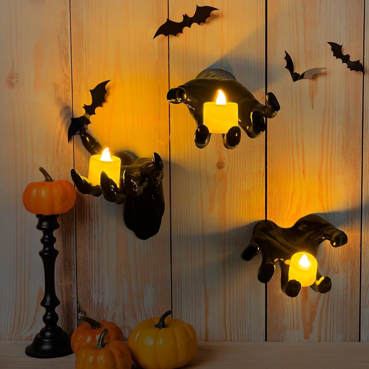 Three glossy black wall-mounted hands holding warm LED tea lights