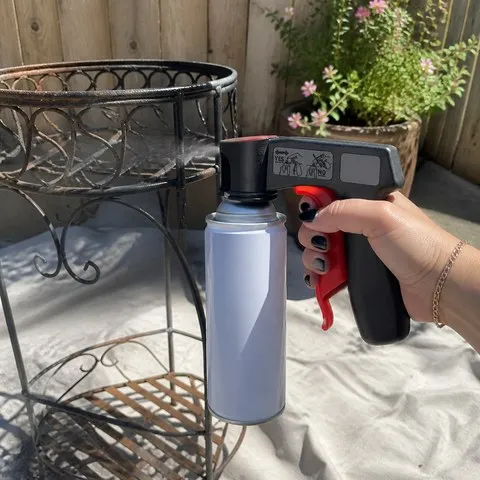 A homeowner using the trigger handle to refresh a patio plant stand