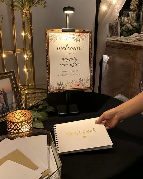 Lighted stand holding a welcome sign beside a wedding guest book