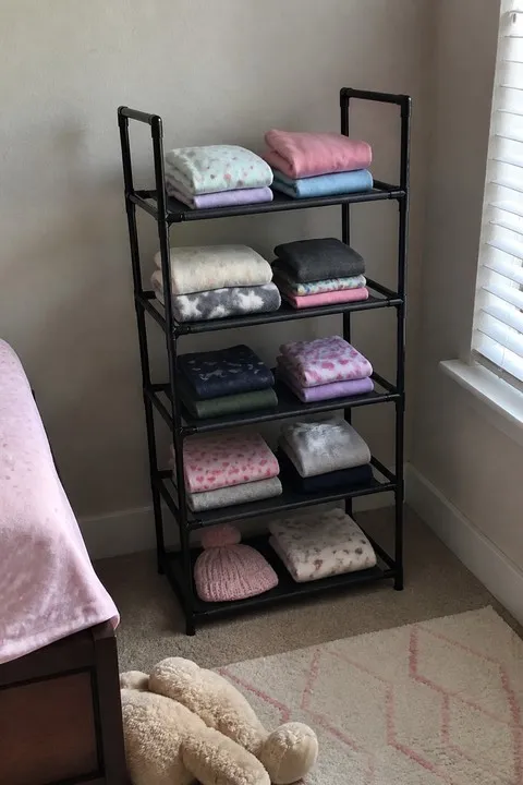 Five-tier rack organizing folded kids clothes in a bedroom corner