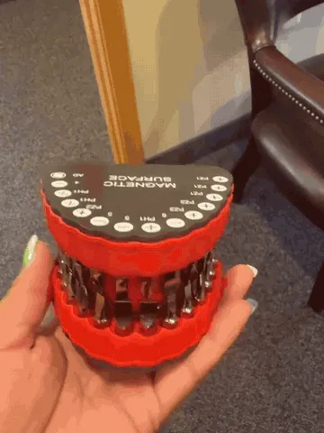 The red denture-shaped bit organizer opening and closing in one hand