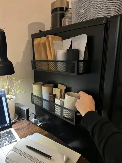 Coffee supplies stored in magnetic racks beside a mini refrigerator