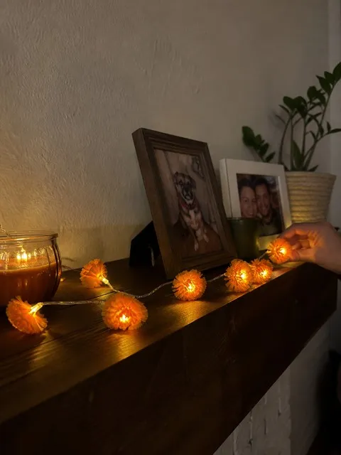 Orange marigold flower lights glowing across a small apartment mantel
