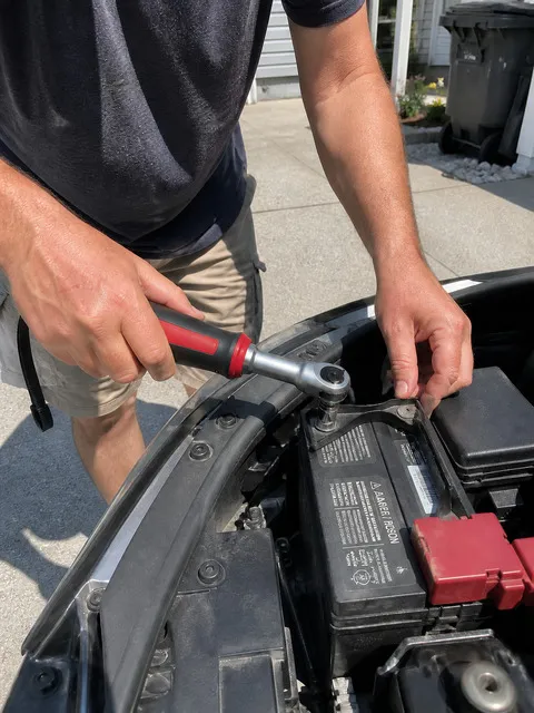 Customer-style smartphone photo using the red power ratchet near a car battery