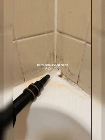 Handheld steam cleaner working through bathroom buildup