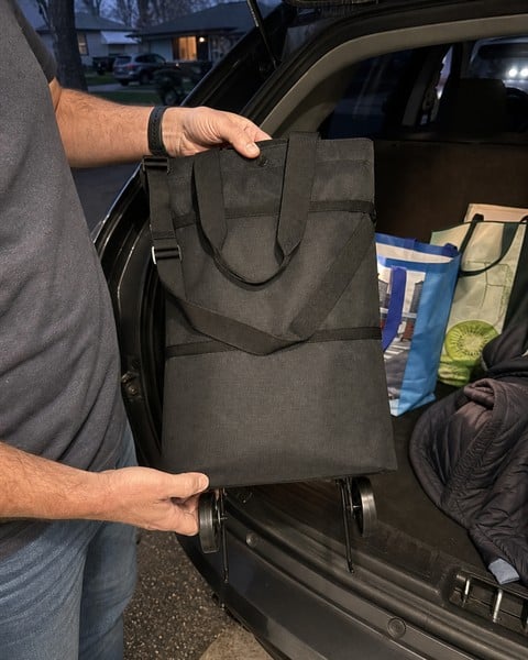 Black folded tote being lifted from a car trunk