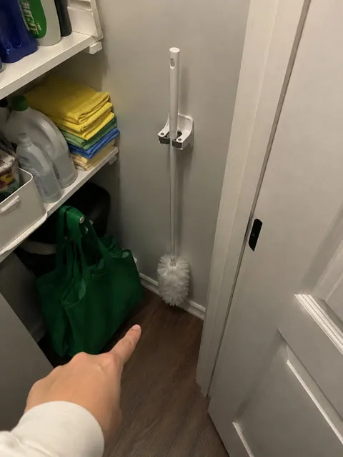 Duster handle stored vertically in a small cleaning closet