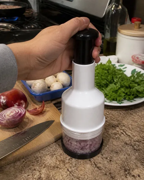 Home cook using the enclosed chopper for onion prep